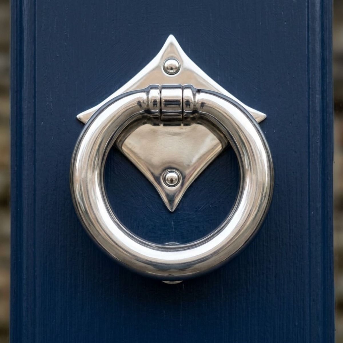 The "Lorien" Ring Door Knocker - Polished Stainless Steel on a Dark Blue Front Door on a Sunny Day - Digital Illustration 