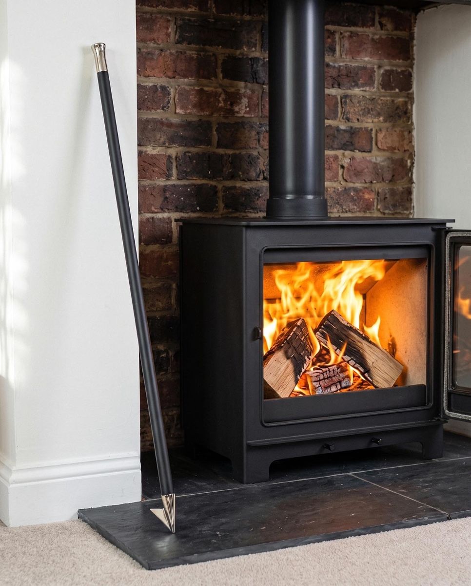 The "Nuri" Bright Chrome Fire Blow Pipe in Front of a Contemporary Fireplace next to a Log Basket - Digital Illustration 