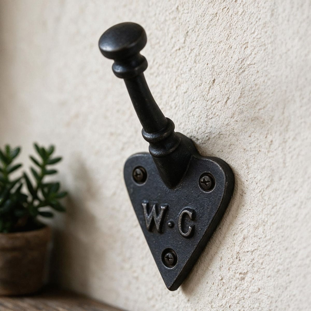 The "W.C" Iron Coat Hook Pictured next to a Shelf on an Interior Wall - Digital Illustration