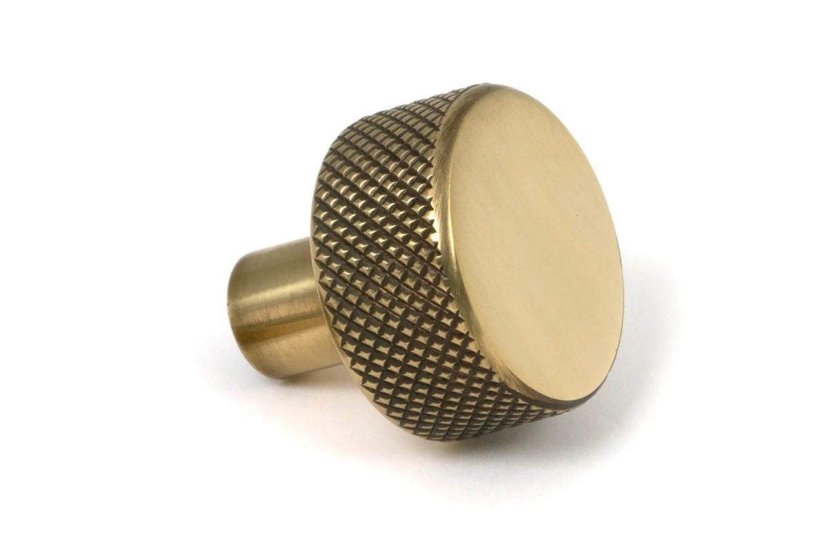 The 25mm "Vesper" Knurled Edge Cabinet Knob in Aged Brass on a White Background Shown from the Side