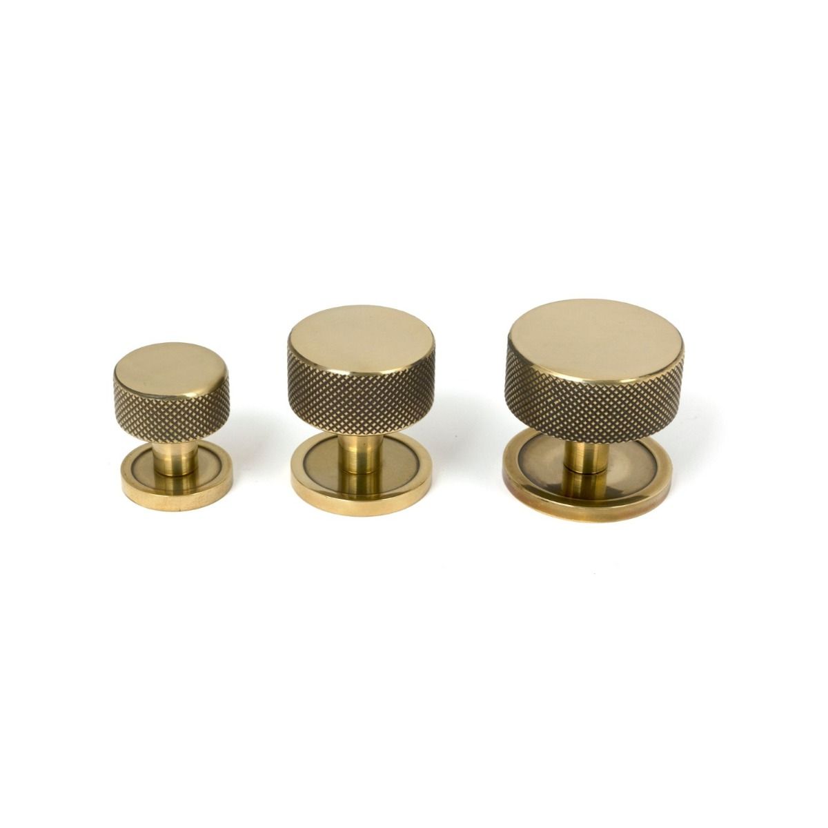 The 25mm Knurled Cabinet Knob on a Plain Rose in Aged Brass Alongside Different Sizes 