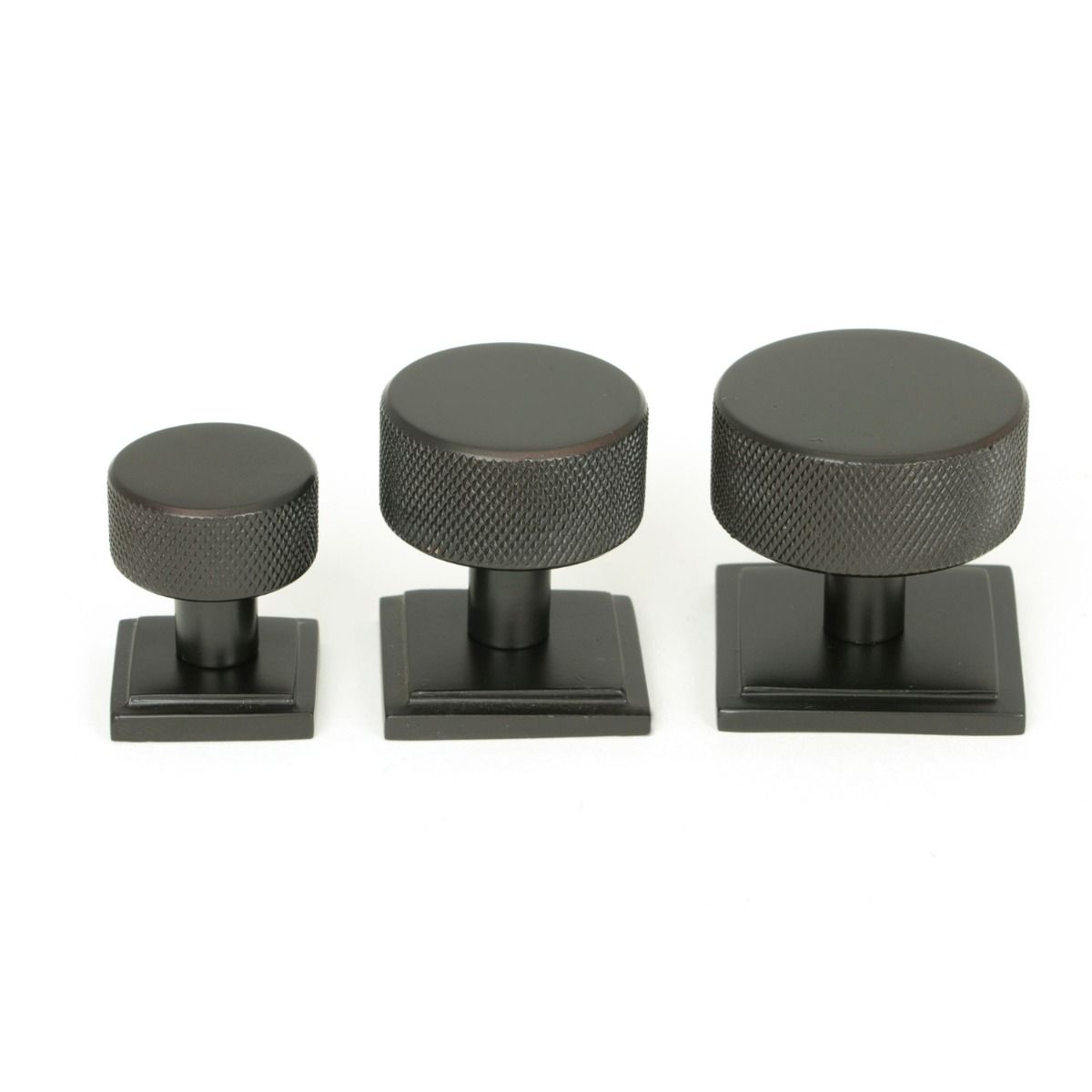 The 25mm Knurled Cabinet Knob on a Square Rose in Aged Bronze Alongside Different Sizes 