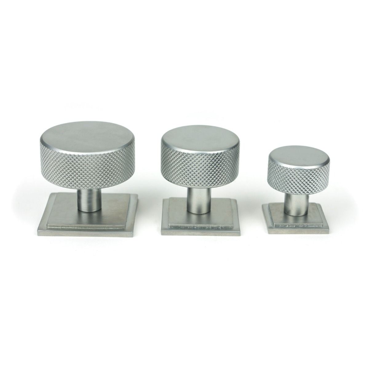 The 25mm Knurled Cabinet Knob on a Square Rose in Satin Chrome Alongside Different Sizes