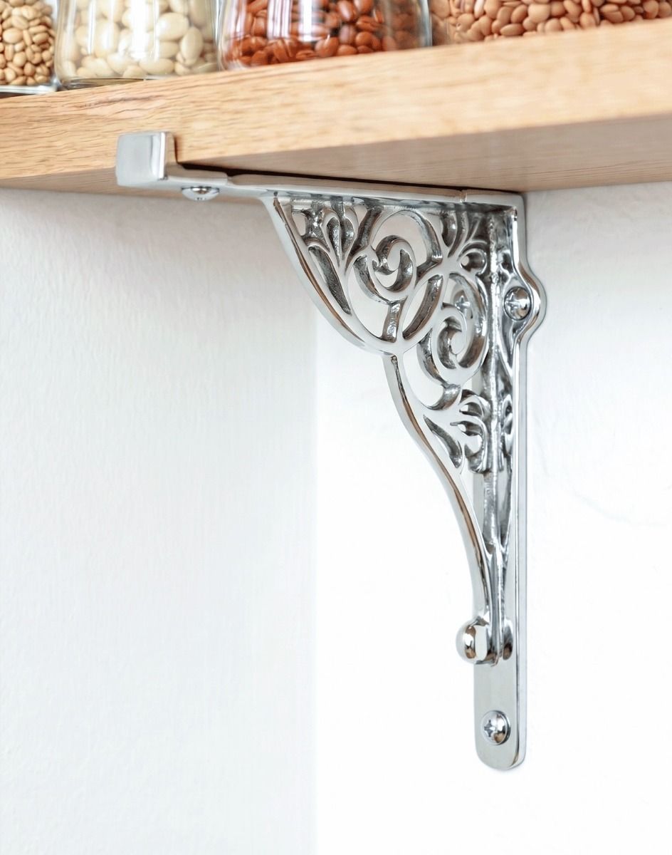The 27cm x 22cm Entwined Scroll Bright Chrome Shelf Bracket Mounted on a White Coloured Kitchen Wall Supporting a Wooden Shelf - Digital Illustration