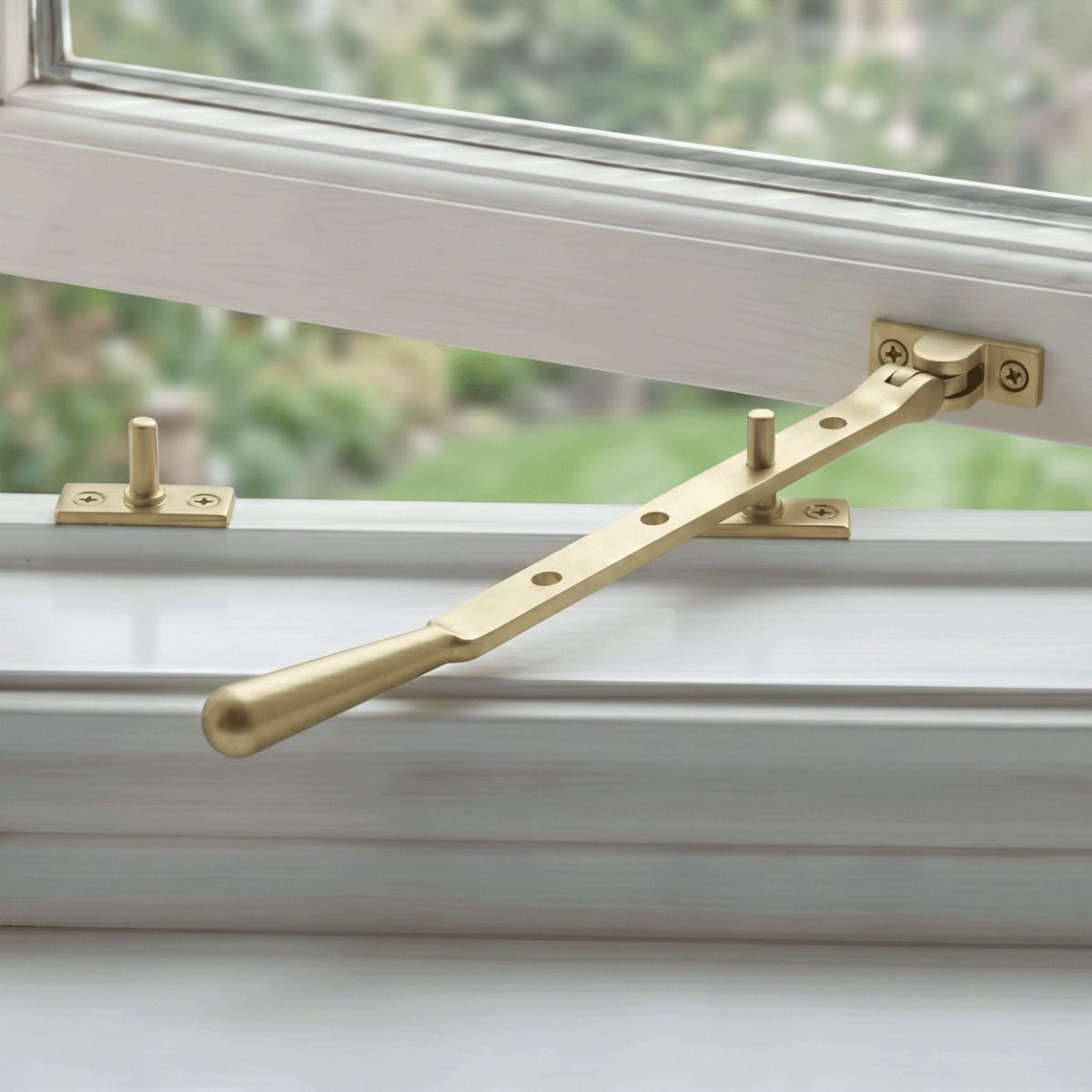 The 296mm 10" Satin Brass Four Pin Window Stay Mounted on a White Window Frame in a Modern Home - Digital Illustration