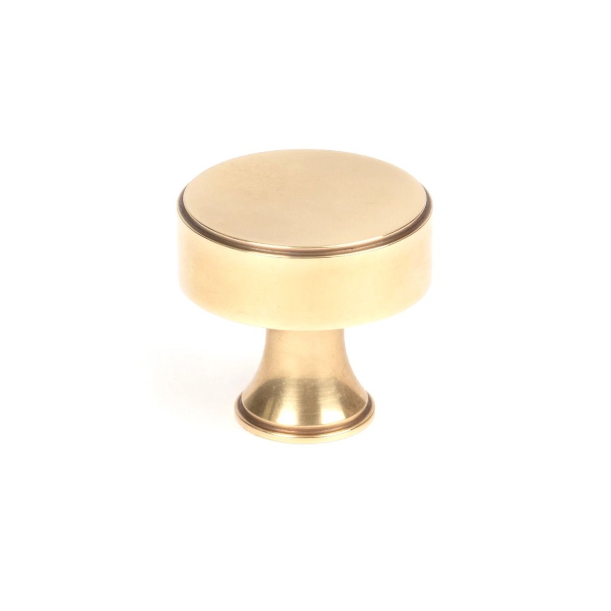 The 32mm "Atelier" Circular Cabinet Knob in Aged Brass on a White Background Stood Upright 