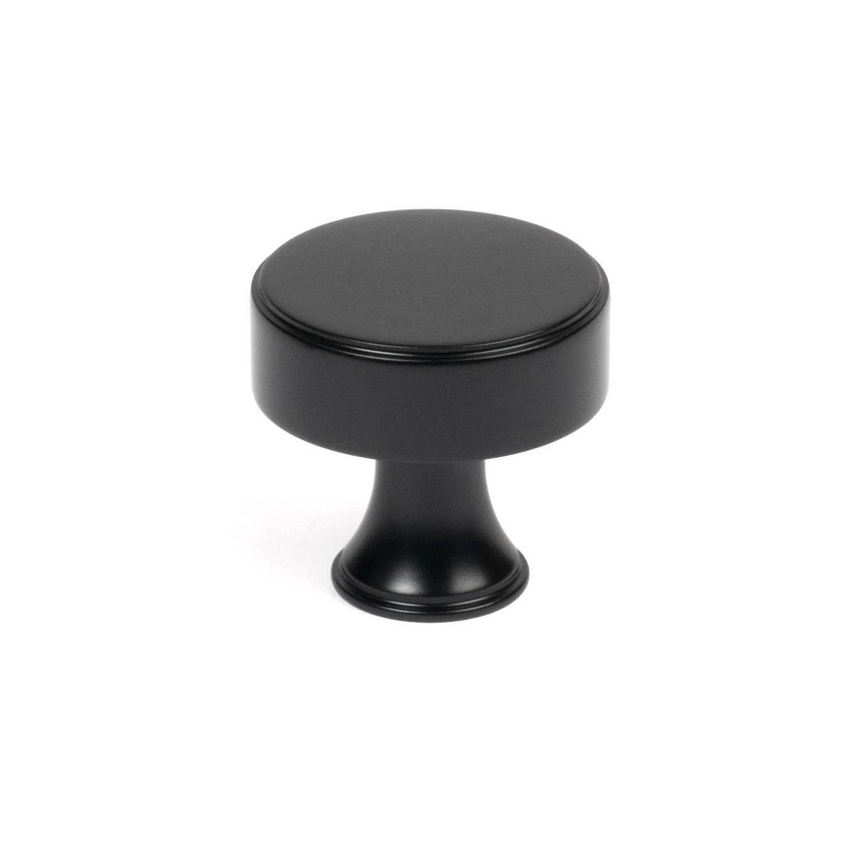 The 32mm "Atelier" Circular Cabinet Knob in Matt Black on a White Background Stood Upright