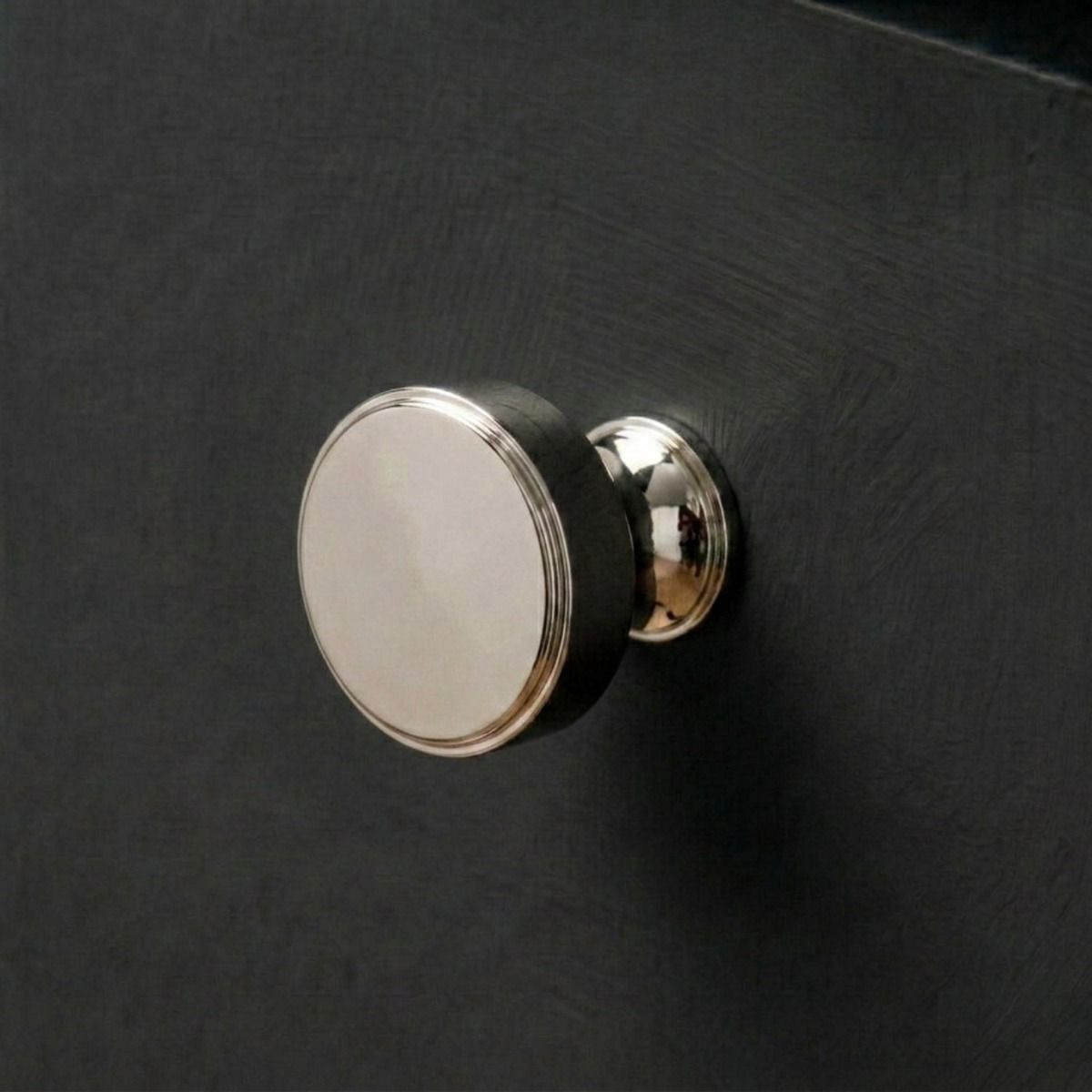 The 32mm "Atelier" Circular Cabinet Knob in Polished Nickel Designed for Kitchen Cupboards and Displayed on a Dark Wooden Drawer - Digital Illustration 