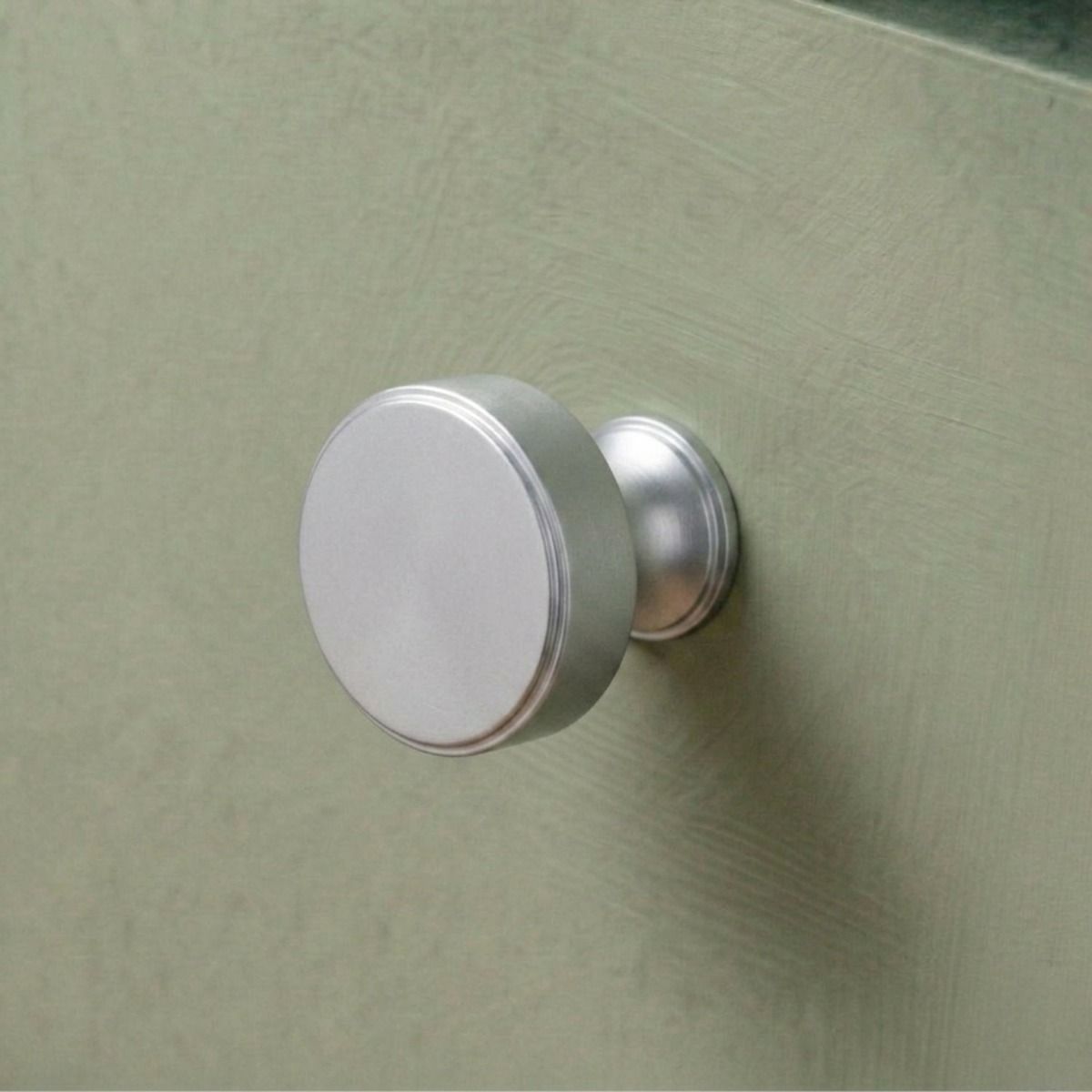 The 32mm "Atelier" Circular Cabinet Knob in Satin Chrome Designed for Kitchen Cupboards Mounted on a Mint Green Drawer - Digital Illustration