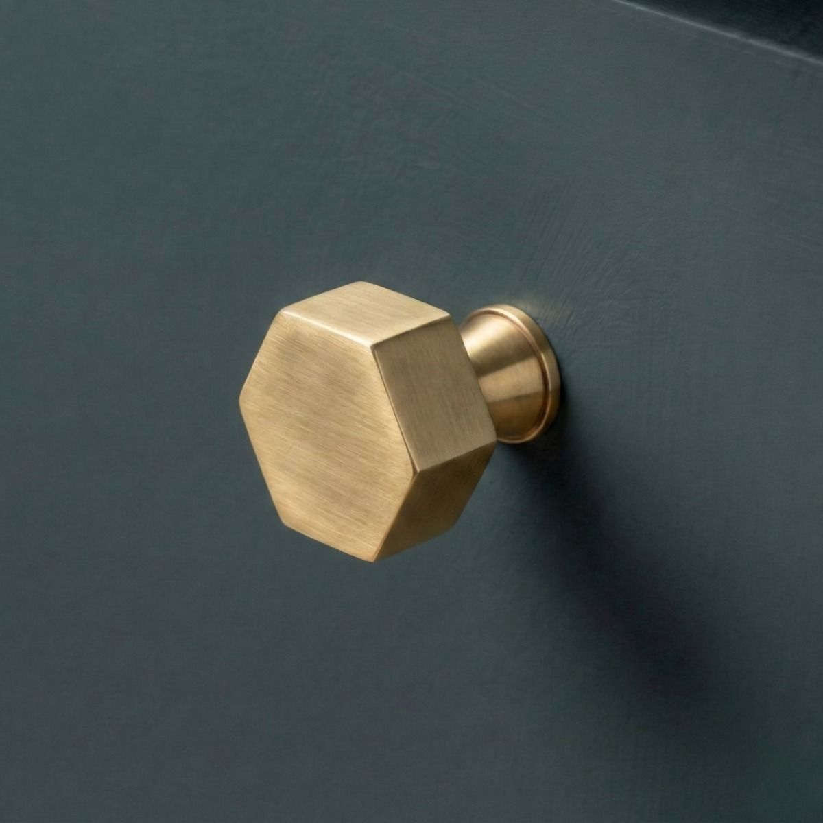 The 32mm "Vanguard" Hexagonal Cabinet Knob in Aged Brass Mounted on a Blue Kitchen Cupboard - Digital Illustration