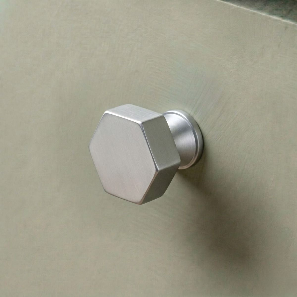 The 32mm "Vanguard" Hexagonal Cabinet Knob in Satin Chrome Displayed on a Sage Green Kitchen Cabinet Drawer - Digital Illustration