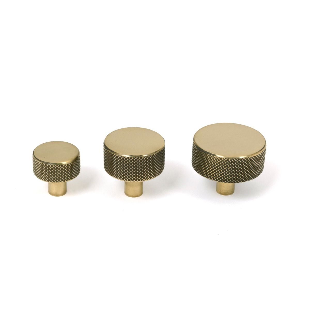The 32mm Knurled Cabinet Knob (No Rose) in Aged Brass Alongside Different Sizes on a White Background