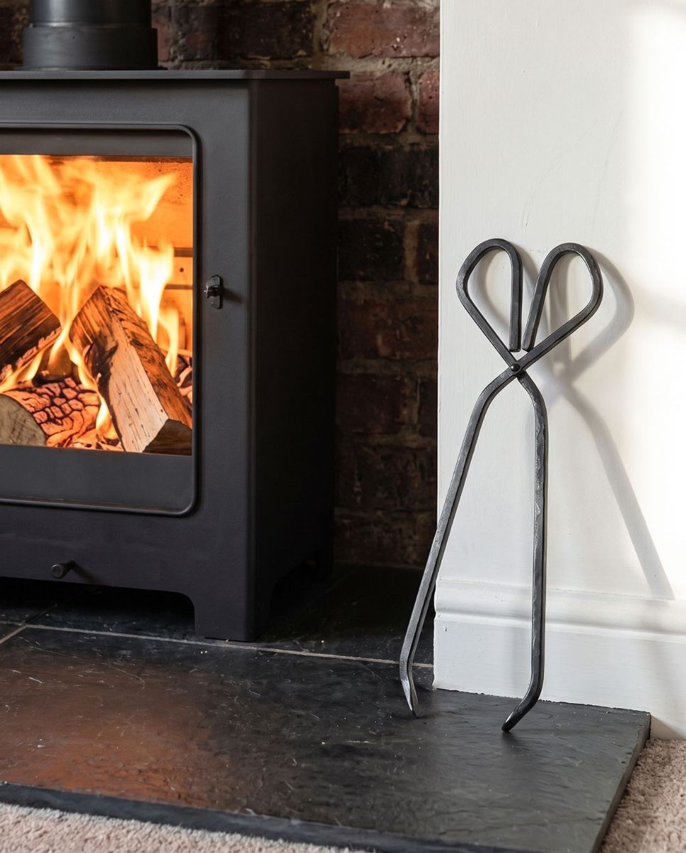 The 37cm Black Iron Fireplace Log Tongs  on a Stone Tiled Floor Next to a Log Basket - Digital Illustration