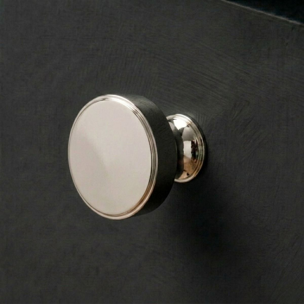 The 38mm "Atelier" Circular Cabinet Knob in Polished Nickel Designed for Kitchen Cupboards and Displayed on a Dark Wooden Drawer - Digital Illustration 