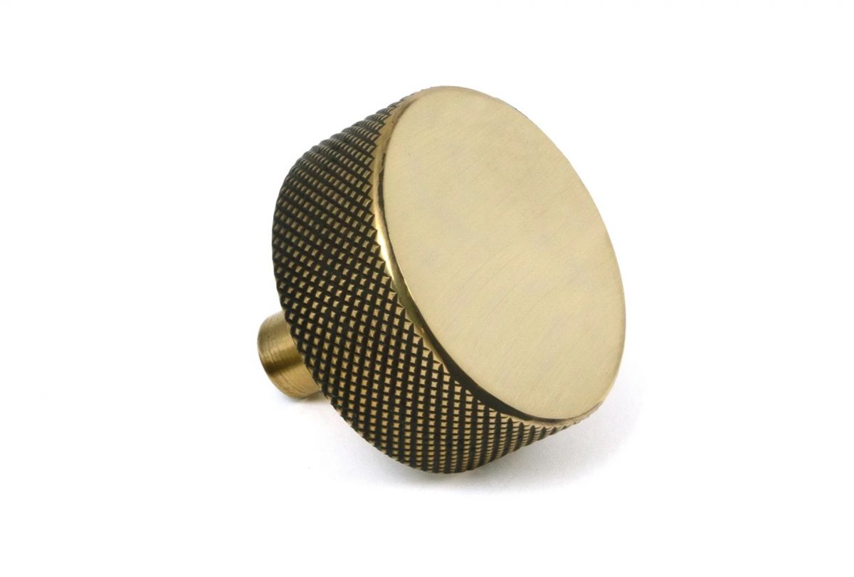 The 38mm "Vesper" Knurled Edge Cabinet Knob in Aged Brass on a White Background Shown from the Side