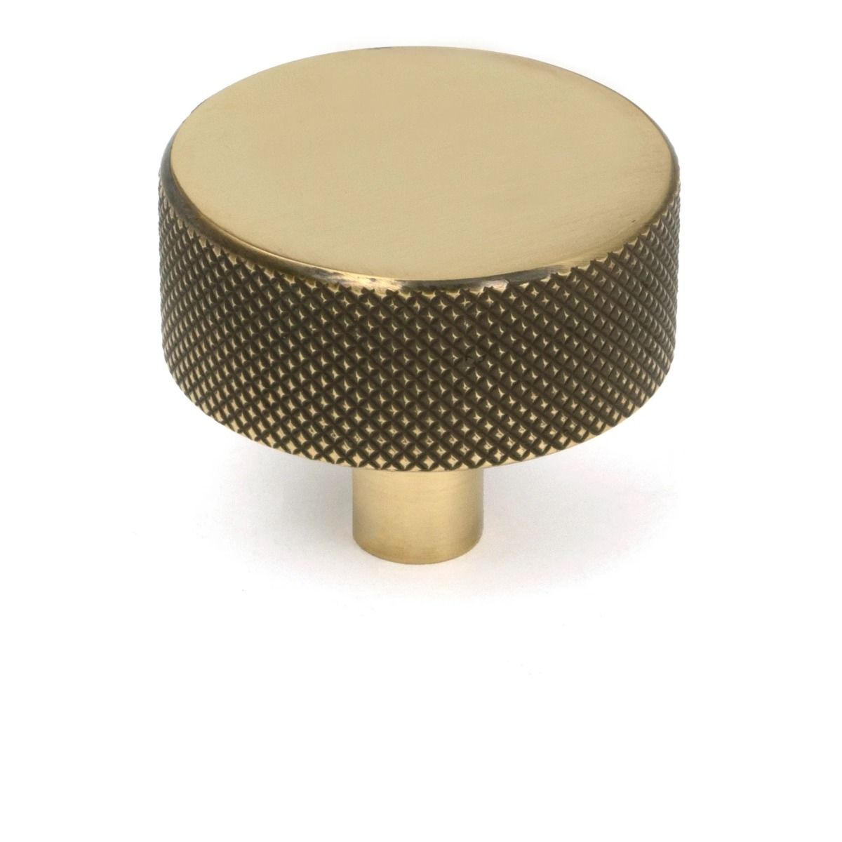 The 38mm "Vesper" Knurled Edge Cabinet Knob in Aged Brass on a White Background Shown Stood Upright 