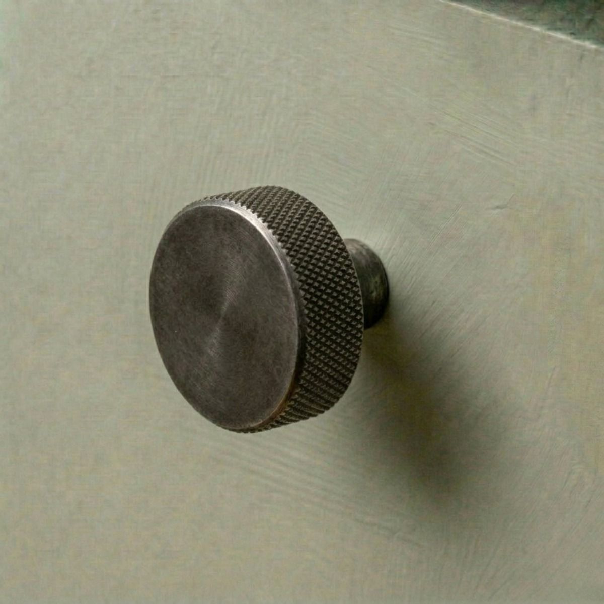 The 38mm "Vesper" Knurled Edge Cabinet Knob in Pewter Designed for Kitchen Cupboards and Displayed on a Green Drawer - Digital Illustration 