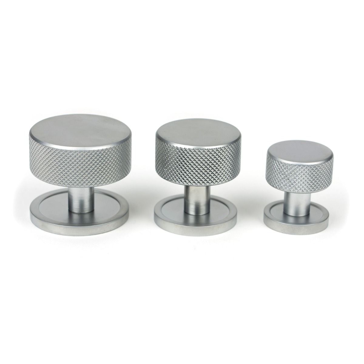 The 38mm Knurled Cabinet Knob on a Plain Rose in Satin Chrome Next to Other Available Sizes on a White Background