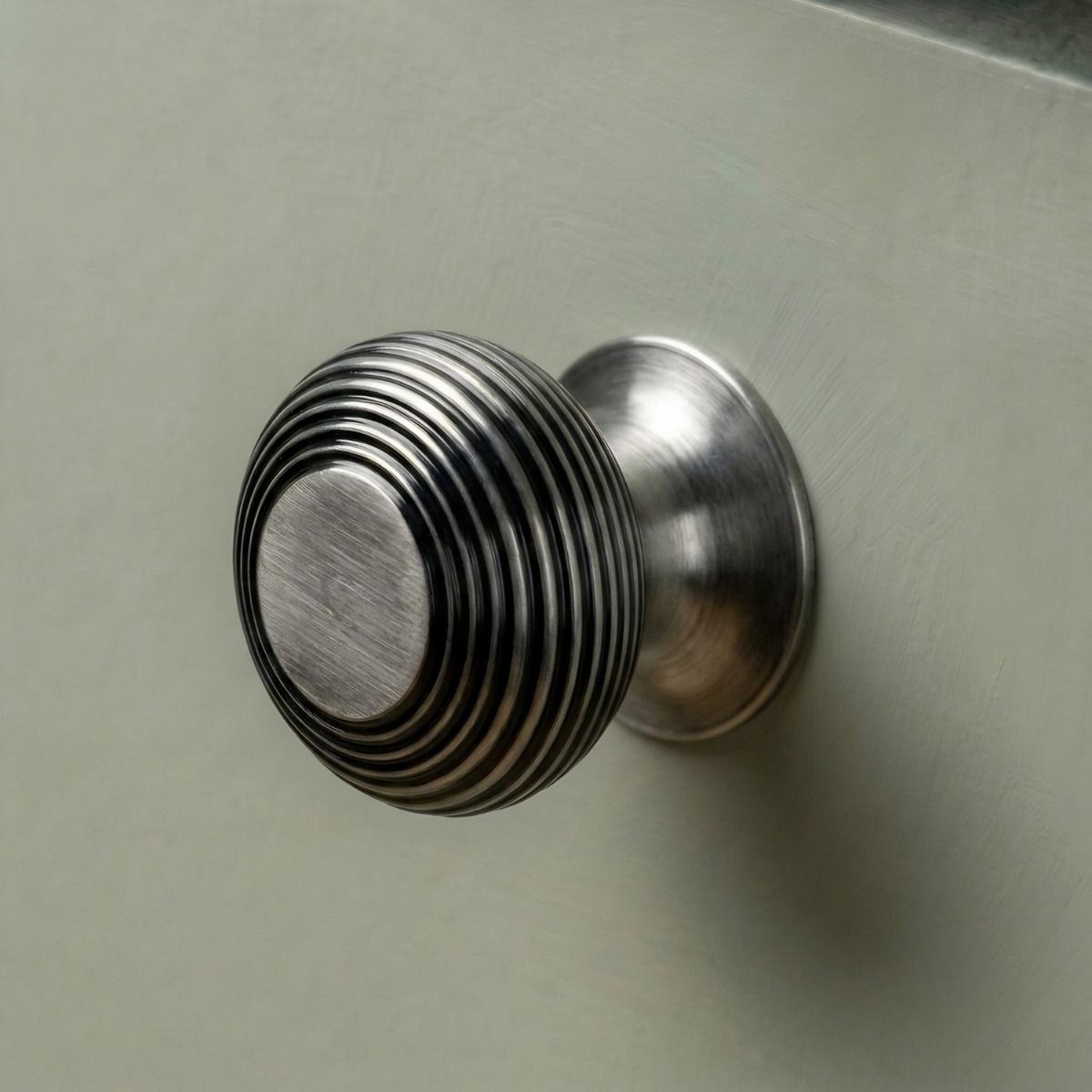 The 40mm "Garrison" Ribbed Beehive Knob in a Pewter Finish Fitted on to a Sage Green Kitchen Cupboard - Digital Illustration