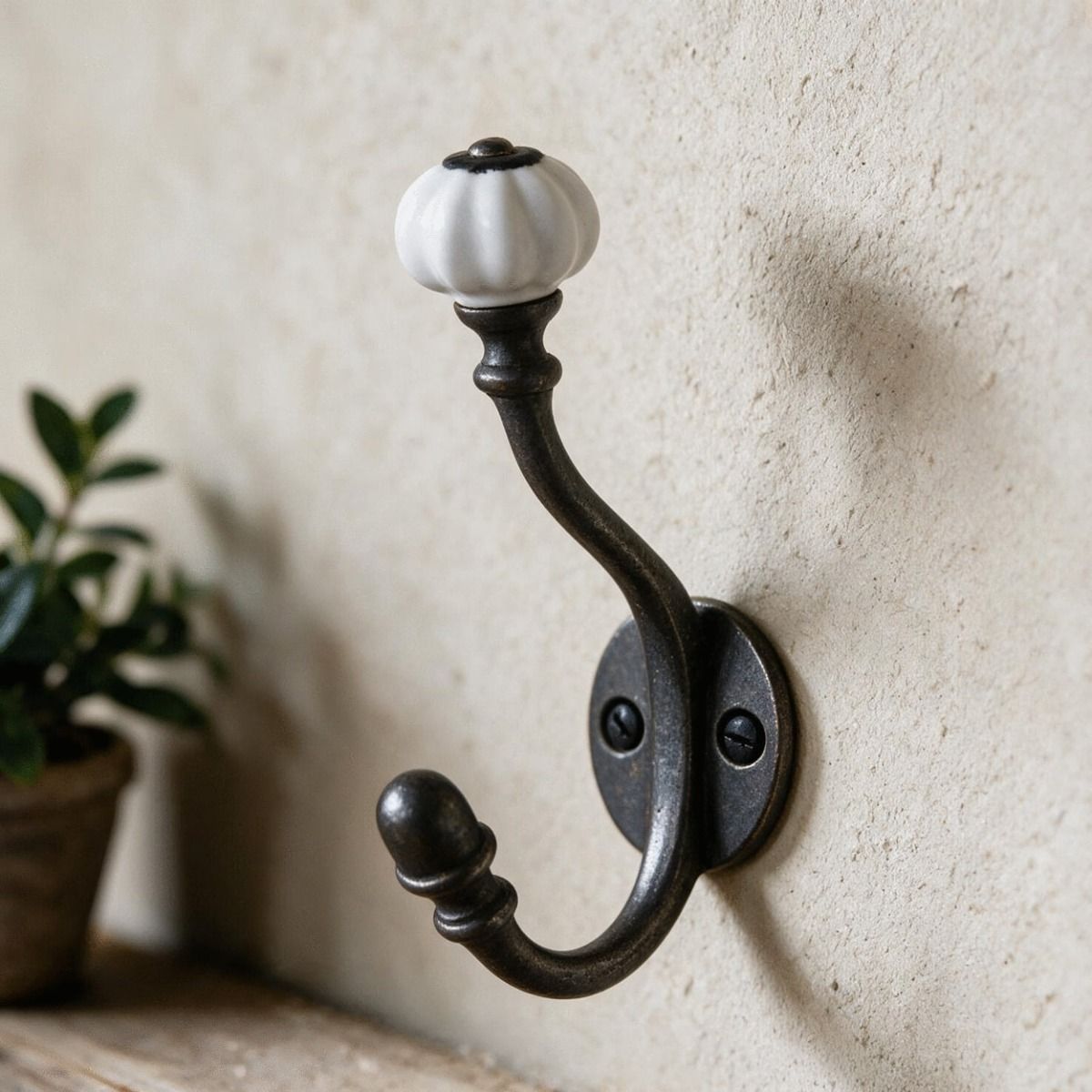 The 5" Ceramic Shell Tip Iron Coat Hook Shown Close up next to a Shelf on a Wall - Digital Illustration