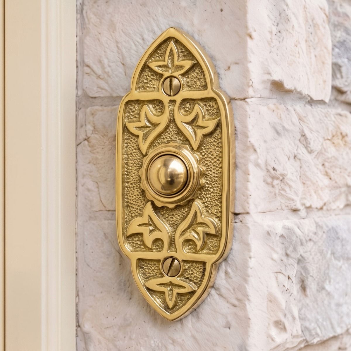 The "Adie Amus" Polished Brass Antique Gothic Bell Push on a Stone Wall next to a Cream Coloured Front Door - Digital Illustration 
