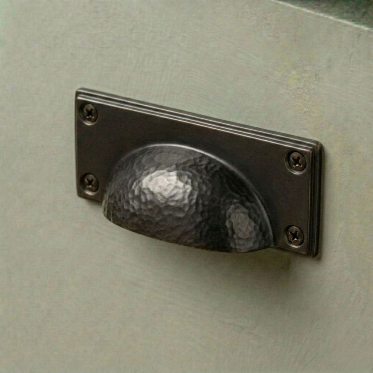 The Aged Copper Rectangular Drawer Pull with Curved Hammered Handle Mounted on a Green Kitchen Cupboard in a Contemporary Home - Digital Illustration 