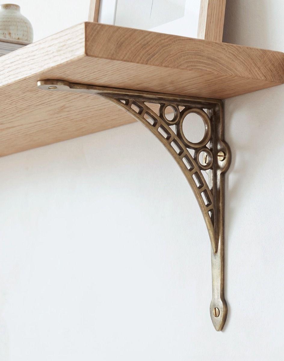 The Antique Brass 20cm x 22cm "Iron Bridge" Shelf Bracket Mounted on a White Coloured Living Room Wall - Digital Illustration.
