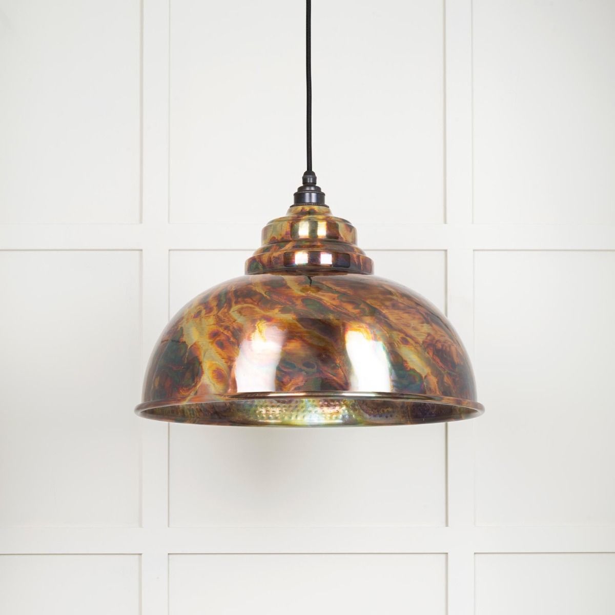 The Arcus Spun Pendant Light in Burnished Finish Shown Lit up on a White Panelled Background
