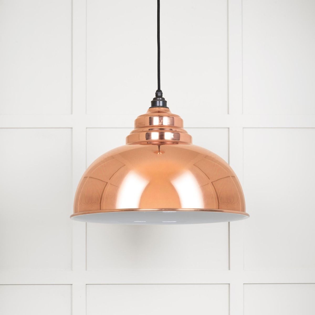 The Arcus Spun Pendant Light in Copper and Glossy White Shown on a White Panelled Background