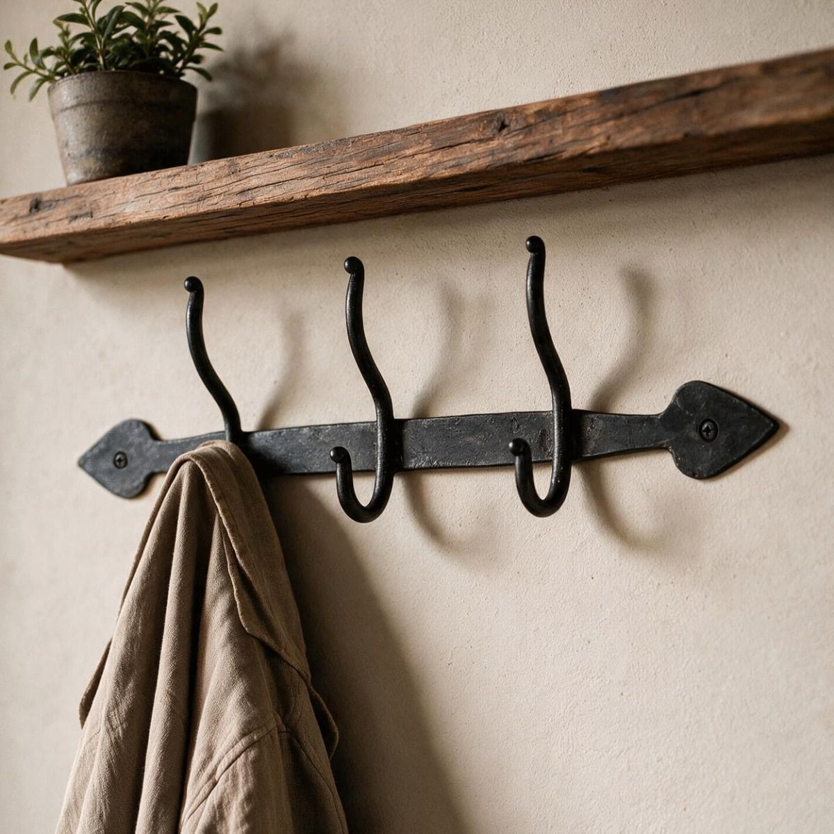 The Beeswax Blacksmith Triple Coat Hook Positioned Under a Timber Shelf in a Hallway - Digital Illustration