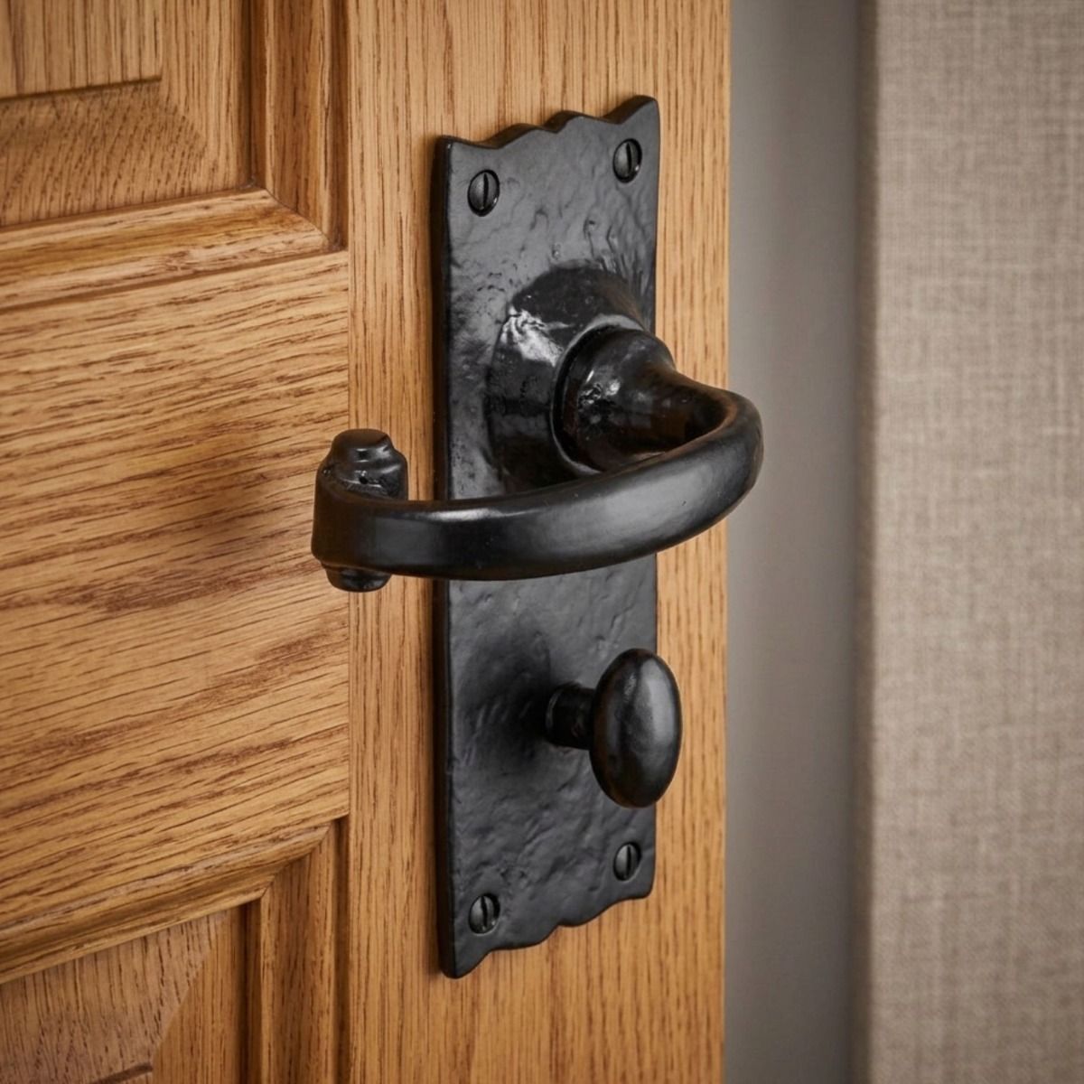 The Black Antique Wide Backplate Bathroom Door Handle on an Oak Door in a Contemporary Home - Digital Illustration 