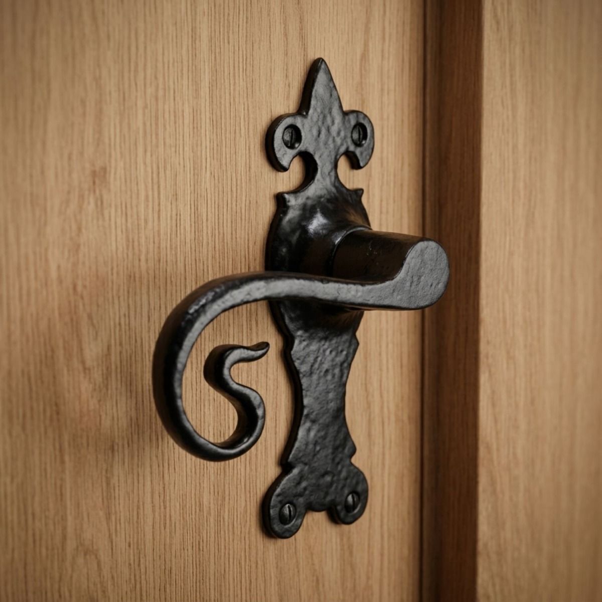 The Black Fleur-de-Lis Monkey Tail Lever Door Handle Mounted on a Pine Door Next to a Matching Door Frame - Digital Illustration