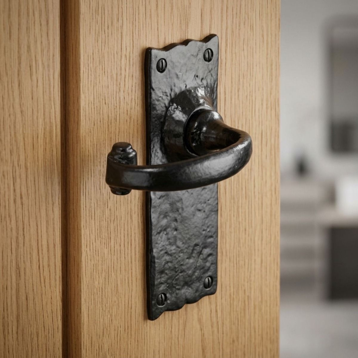 The Black Wide Backplate Scalloped Lever Latch Door Handle on a Light Wooden Door Leading to a Modern Living Room Setting - Digital Illustration 