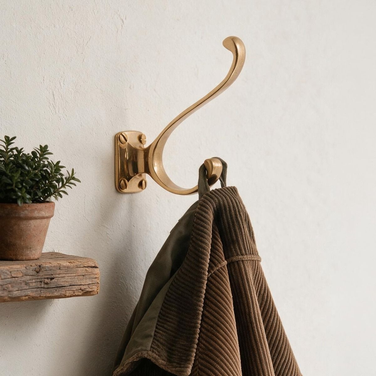 The Brass Hat and Coat Hook with Square Back Plate on a Cream Wall with a Coat Hanging From it - Digital Illustration 