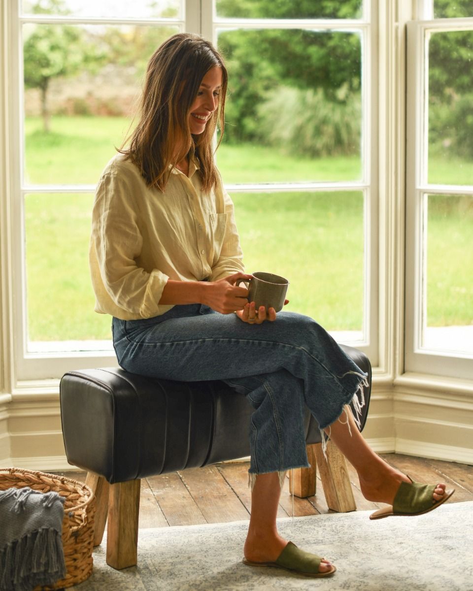 The Brodie Mango Wood & Black Leather Bench With Woman Sat Down for Scale
