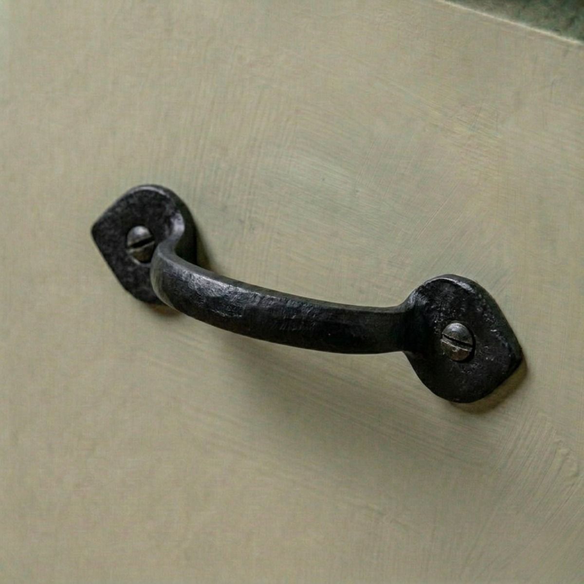 The Cast Iron Arrow Tip Design Pull Handle Mounted on a Green Kitchen Cabinet - Digital Illustration