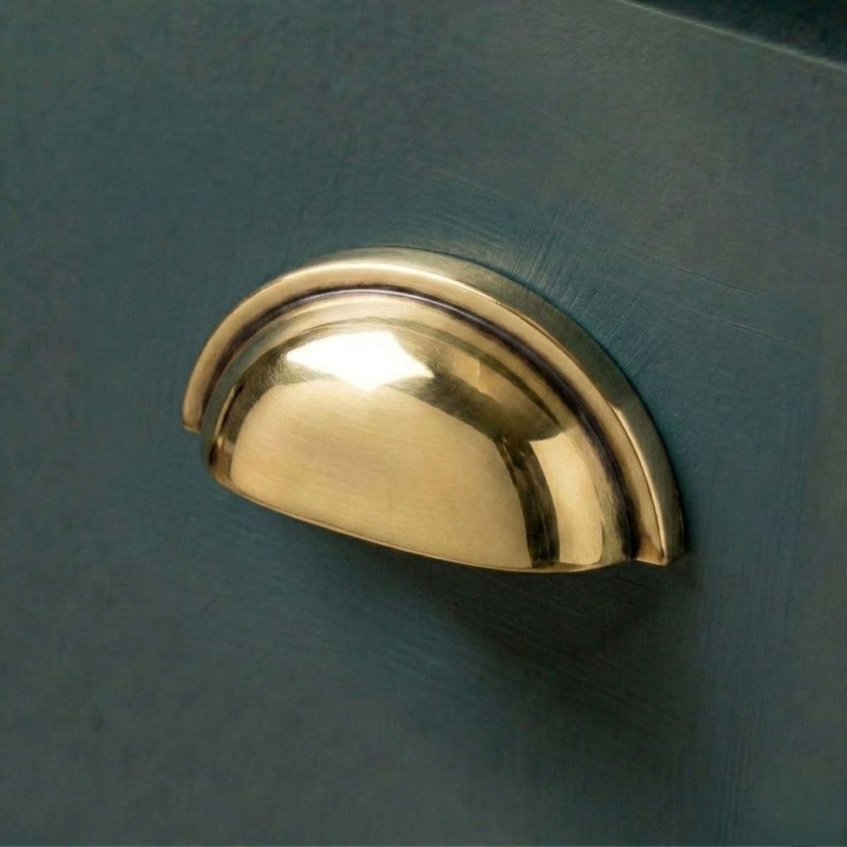 The Concealed Drawer Cup Pull Handle in an Aged Brass Finish Fitted on a Blue Kitchen Cupboard Drawer - Digital Illustration
