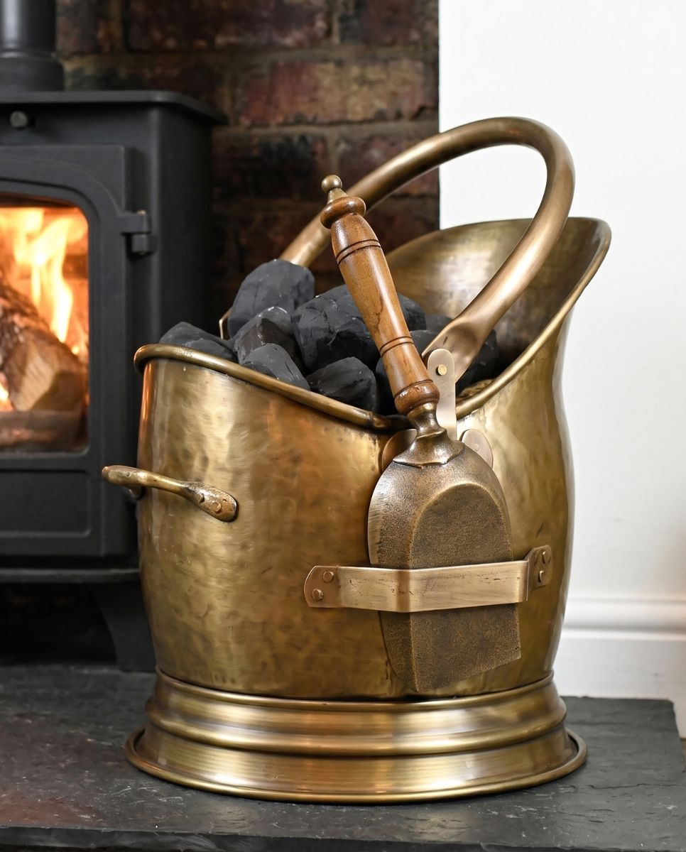 The Coven Antique Bronze Finish Coal Scuttle with Shovel on a Stone Tiled Floor Next to a Log Burner - Digital Illustration