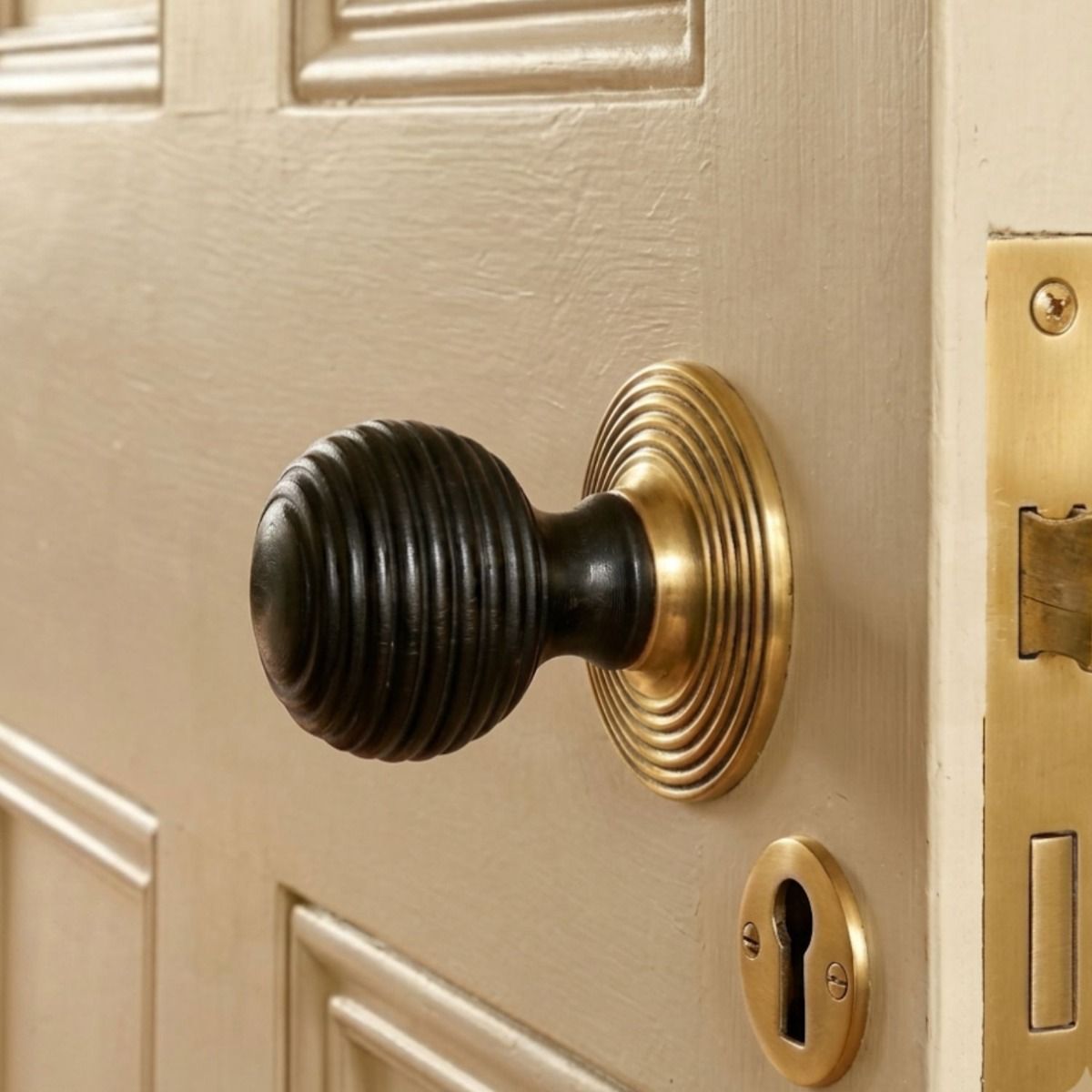 The Ebony Beehive door knobs With Polished Brass Rose on a Cream Door with Matching Brass Keyhole - Digital Illustration