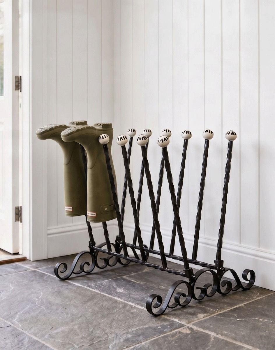 The Haldenwall 6 Pair Boot Rack in Black Placed in a Stone Tiled Cottage Porch Close up View - Digital Illustration 