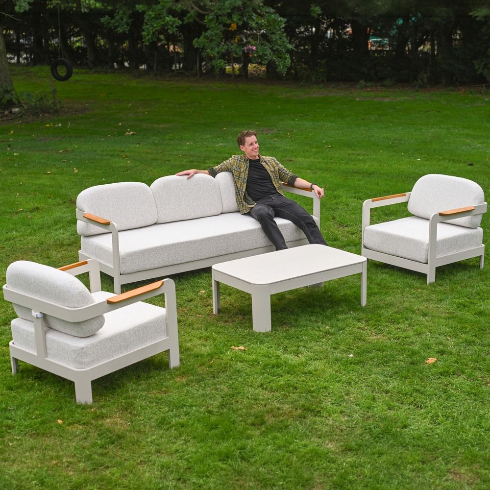 The Horizon 4 Piece Patio Suite with a Man Relaxing on the Sofa on a Garden Lawn