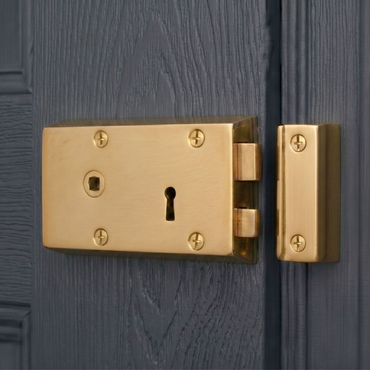 The Left Handed "Gallus" Small Polished Brass Rim Lock Fixed on a Navy Blue Traditional Wooden Door - Digital Illustration
