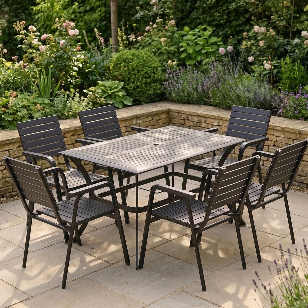 The Linea 6-Seater Outdoor Garden Dining Set in Black in a Sunny Low Walled Garden Surrounded by Plants