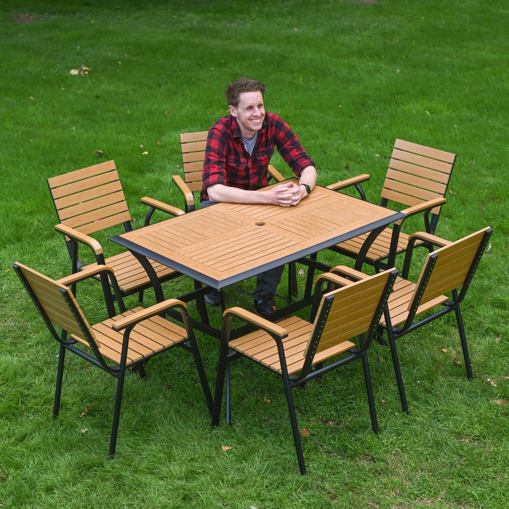 The Linea 6-Seater Outdoor Garden Dining Set in Teak Showing a High Angle of a Man in a Red Shirt Sat at the Table