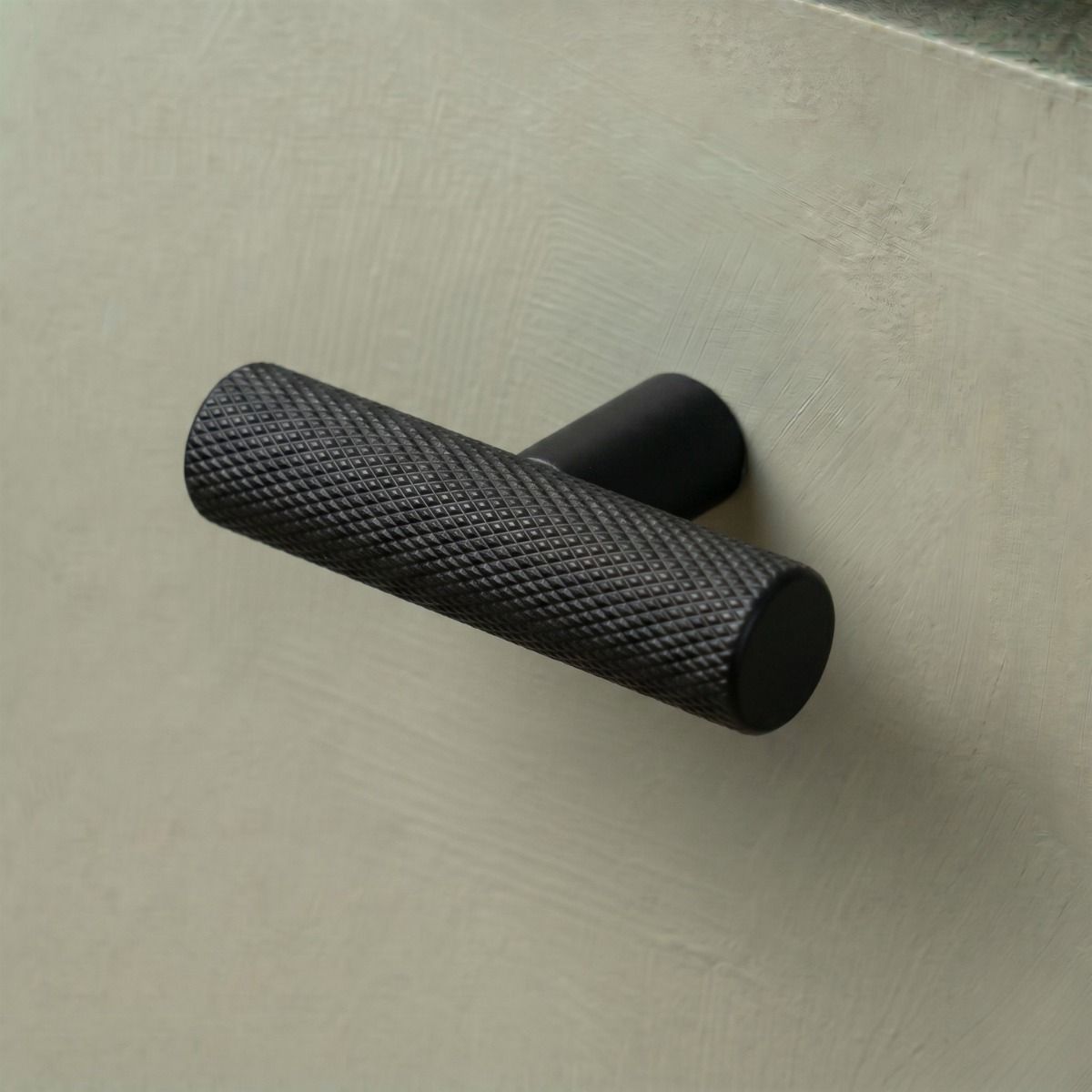 The Matt Black "Astor" Knurled Industrial T-Bar Cabinet Handle Mounted on a light Green Kitchen Cupboard Drawer - Digital Illustration