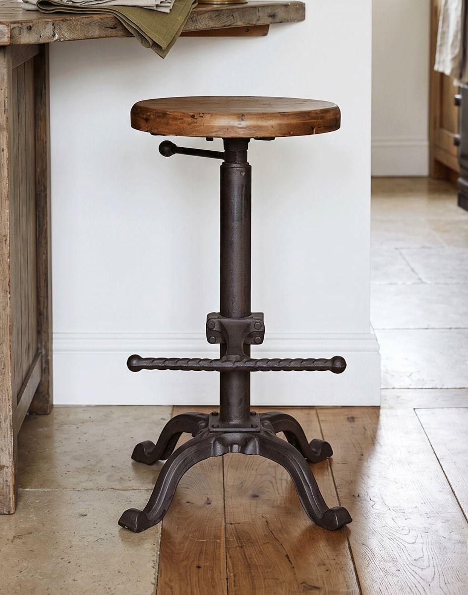 The “Milkwood Farm” Cast Iron Stool with Wooden Seat Next to a Breakfast Bar in.a Kitchen Setting - Digital Illustration