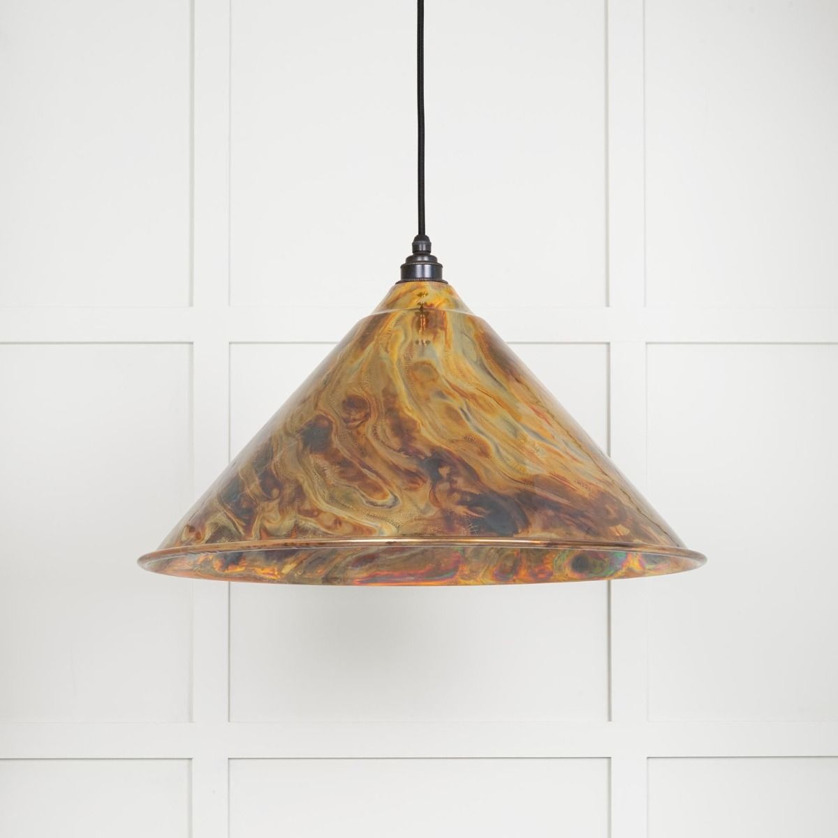 The Nidus Pendant Light in a Burnished Finish on a White Panelled Background with Light on