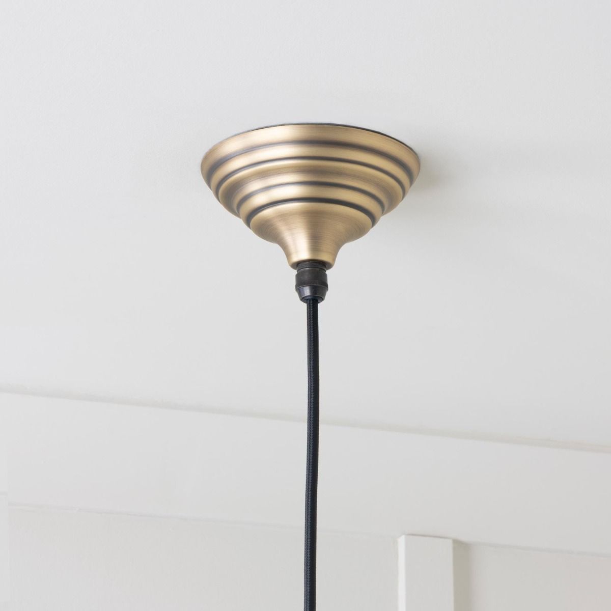The Nidus Pendant Light in Aged Brass Showing a Close up of the Rose