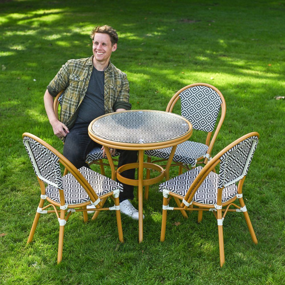 The Orbis Diamond 4-Seater Bistro Dining Set in Black & White With a Man Sat down on a Chair on a Garden lawn