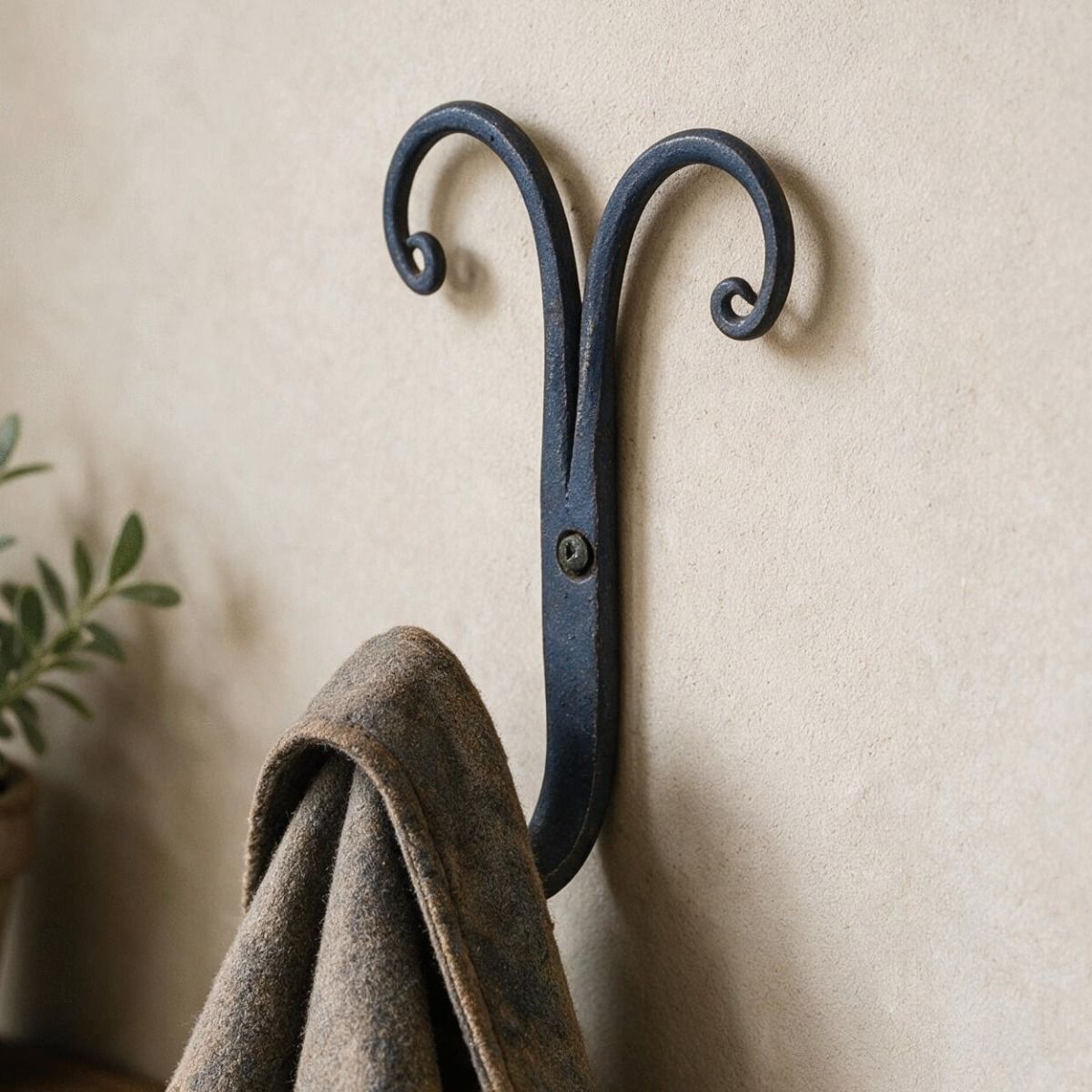The "Rams Horn" Scrolled Iron Coat hook Shown on a Wall with a Coat Hung up on it - Digital Illustration